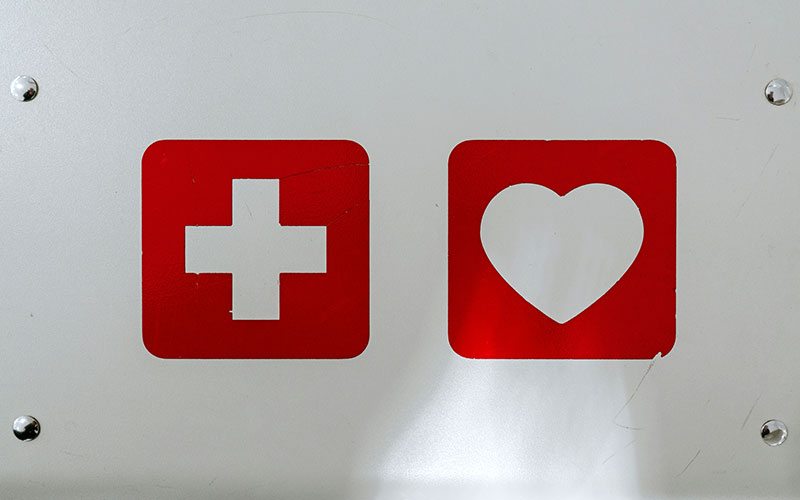 Medical symbols, in white on red, of plus and heart on metal